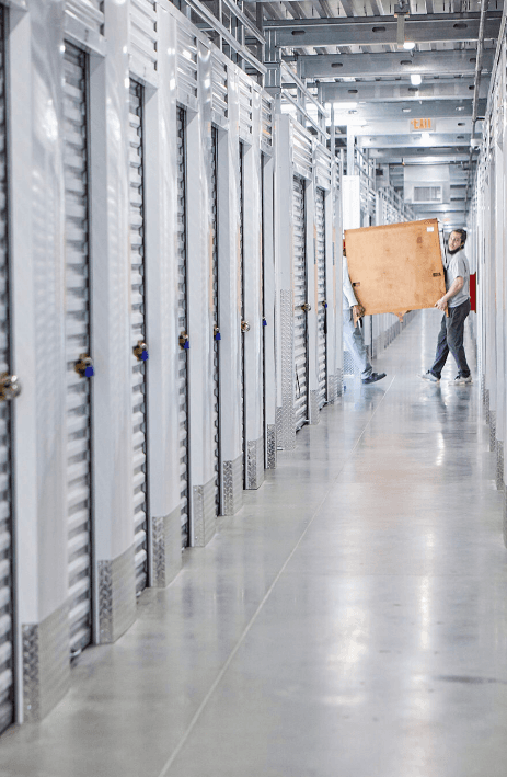 Instalación de self-storage: clientes trasladando mobiliario por el pasillo de trasteros